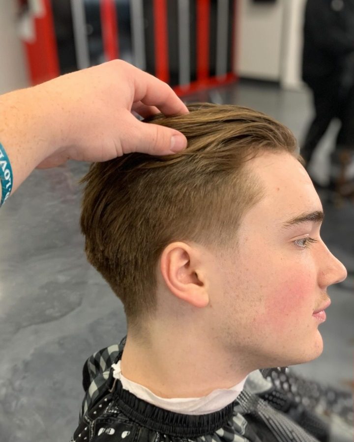 Side profile of a client with a longer swept-back top and a clean low taper