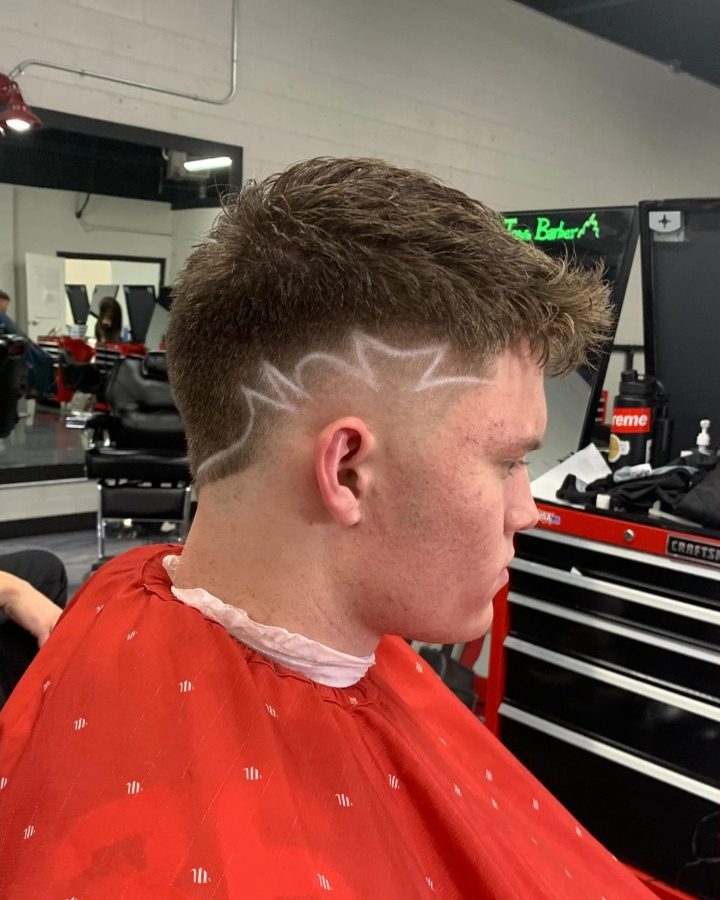 Side view of a textured cut with a burst fade and a lightning-style design
